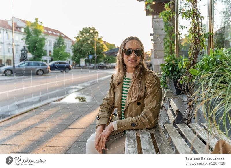 Eine Frau mit Sonnenbrille sitzt an einem Tisch in einem Straßencafé Freude Erwachsener Lächeln zufrieden Selbstvertrauen reales Leben Lifestyle positiv