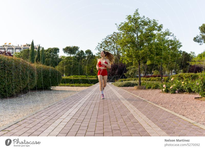 Eine energiegeladene junge Frau beim Laufen im Park rennen Joggen Fitness Übung aktiver Lebensstil Gesundheit und Wohlbefinden Outdoor-Aktivität Natur sportlich