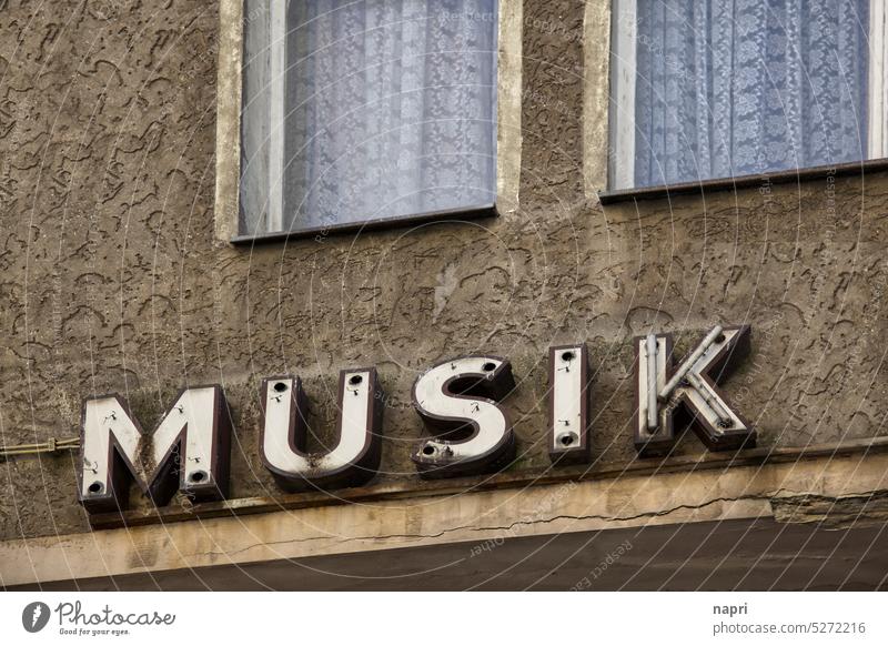 MUSIK bleibt | Alte, defekte Leuchtreklame auf unsanierter Hausfassade. Musik Buchstaben Typographie retro alt marode kaputt Vintage trist Vergangenheit