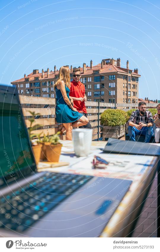 Pärchen, das sich in der Kaffeepause auf dem Dach eines Büros mit seinen Kollegen unterhält Paar Partner sprechend Dachterrasse Terrasse Business Geschäftsleute