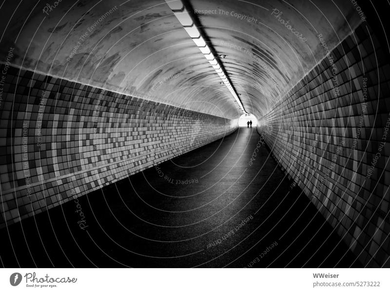Zwei Menschen erreichen Hand in Hand das Ende eines langen Tunnels Unterführung Fußgänger Perspektive Fluchtpunkt Licht Paar zusammen gemeinsam Zweisamkeit Ehe
