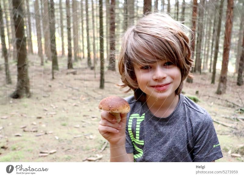 Steinpilz gefunden - Porträt eines Jungen, der im Wald steht und einen Steinpilz in der Hand hält Mensch Kind Pilz Pilze suchen Herbst Natur Farbfoto