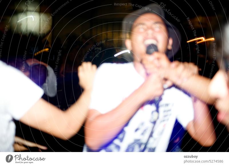 Unscharfe Darstellung eines asiatischen jungen Mannes, der bei einem Hardcore/Punk-Konzert mitsingt Asien Publikum Band jubelnd Konzertbühne Menge mitsingen