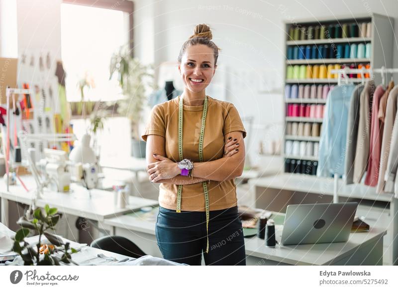 Porträt einer jungen Modedesignerin an ihrem Arbeitsplatz Handwerk Schneidern Herstellung handgefertigt Näherin Kleinunternehmen Nähmaschine Werkstatt Gewebe