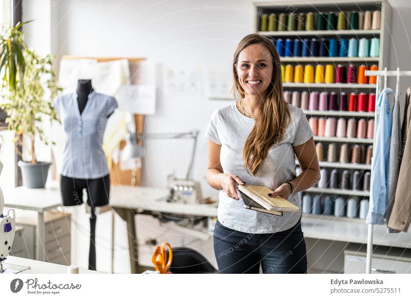 Porträt einer jungen Modedesignerin an ihrem Arbeitsplatz Handwerk Schneidern Herstellung handgefertigt Näherin Kleinunternehmen Nähmaschine Werkstatt Gewebe