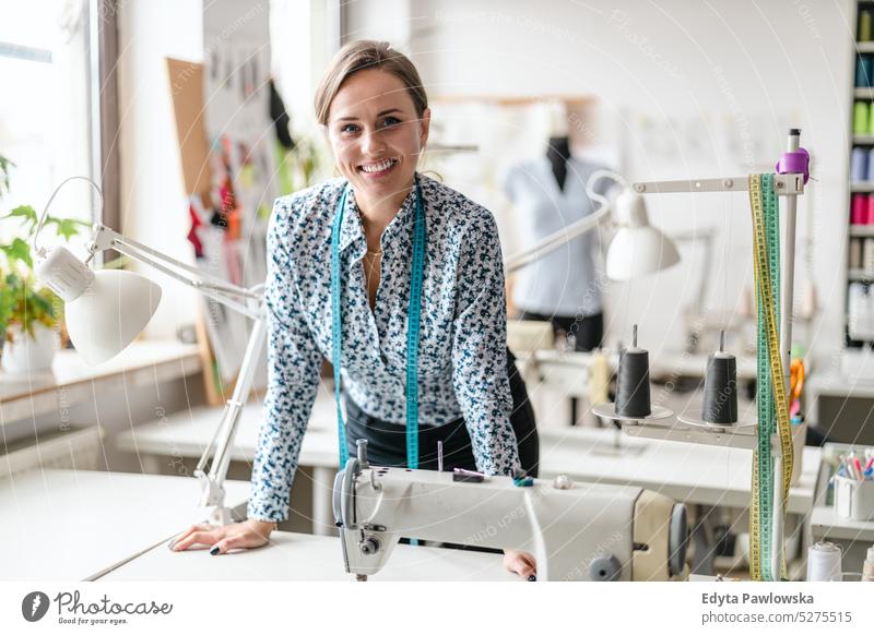 Junge Modedesignerin an ihrem Arbeitsplatz Handwerk Schneidern Herstellung handgefertigt Näherin Kleinunternehmen Nähmaschine Werkstatt Gewebe Hobby Nähen