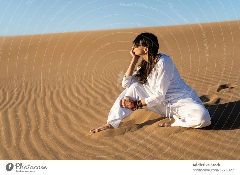 Frau sitzt auf Sand in der Wüste wüst Vitalität Harmonie Zen Blauer Himmel wolkenlos Windstille Stressabbau Achtsamkeit idyllisch friedlich erwärmen frontera