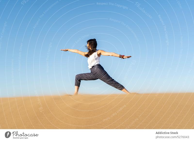 Schlanke Frau übt Yoga in der Haltung des Kriegers II auf sandigem Boden üben Krieger-Pose virabhadrasana beweglich Übung Harmonie Sprit Achtsamkeit la frontera