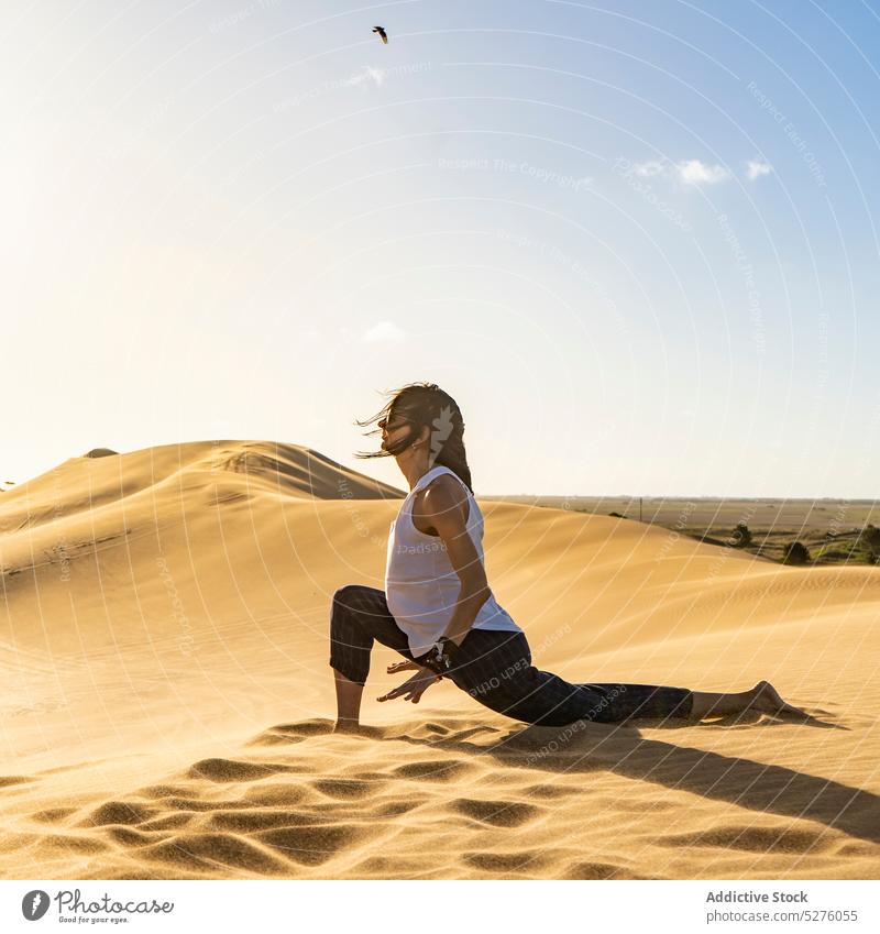 Junge Frau meditiert in Halbmond-Lunge-Pose in der Wüste üben Yoga halbmondförmiger Ausfallschritt anjaneyasana Übung Wellness Harmonie Gesundheit Sprit