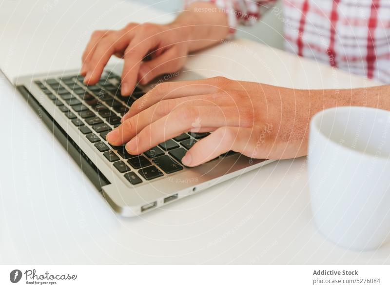 Crop Mann tippt auf einem modernen Laptop Business Schaltfläche Nahaufnahme Computer Datenverarbeitung Schreibtisch Gerät Finger Hand Job Keyboard Tastenfeld