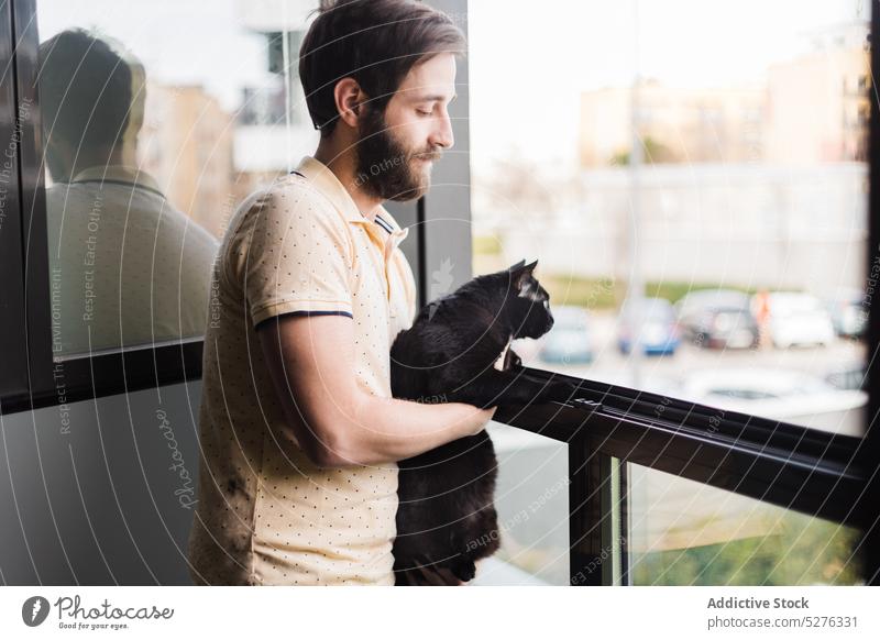 Zufriedener Mann mit schwarzer Katze am Fenster Windstille Besitzer Stadtbild Haustier heimwärts Straße neugierig sich[Akk] entspannen jung männlich lässig Tier