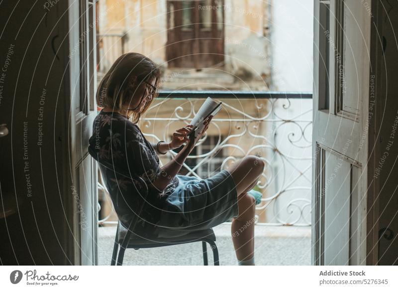 Konzentrierte Frau, die auf dem Balkon ein Buch liest lesen Türöffnung reisen Literatur Hobby Roman Leseratte Windstille jung lässig Kuba Feiertag Tourismus