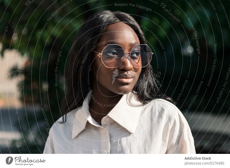 Lächelnde schwarze Frau mit großer Brille positiv Vorschein Sonnenbrille Porträt Park Stil Persönlichkeit Sommer Natur selbstbewusst jung lange Haare