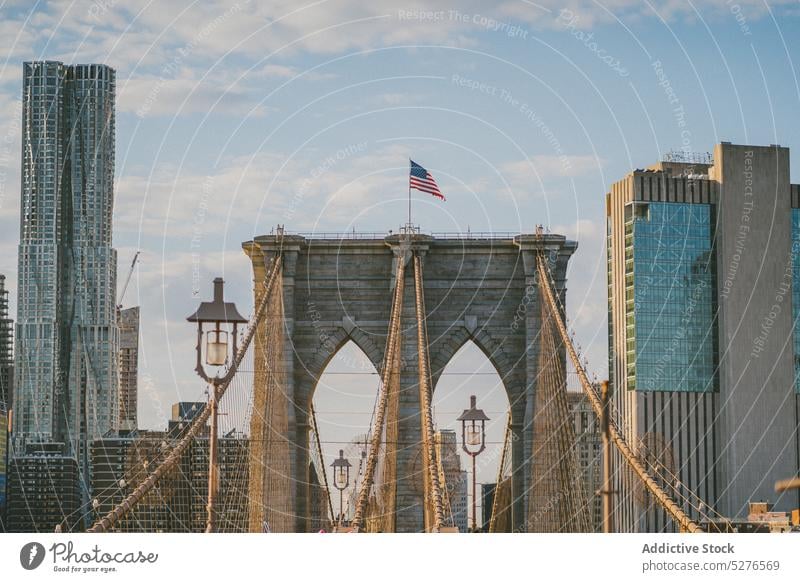 Brooklyn Bridge mit der Flagge der USA an der Spitze Fahne Stadtbild Megapolis Großstadt Gebäude Himmel Fluss Architektur Wolkenkratzer Stadtzentrum wolkig