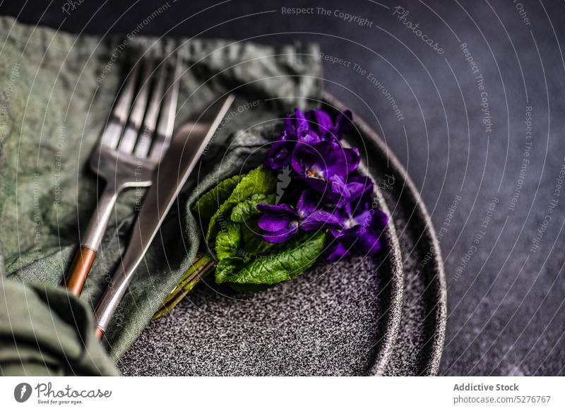 Frühlingshaft gedeckter Tisch mit Bratschenblüten Hintergrund blau Keramik Beton Besteck Abendessen Essgeschirr Ostern Essen festlich geblümt Blume grün