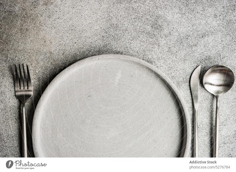 Minimalistisches monochromes graues Tafelset Hintergrund Keramik Beton Besteck Abendessen Essgeschirr Essen Gabel Messer Mahlzeit Essenszeit Minimalismus