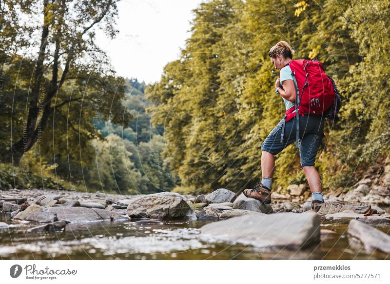 Reisen mit Rucksack Konzeptbild. Backpacker weiblich in Trekking-Stiefel überqueren Berg Fluss. Sommerurlaub Reise Abenteuer reisen Ausflug Urlaub