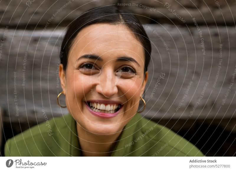 Fröhliche ethnische Frau lächelt und schaut in die Kamera Lächeln Stil Jacke Glück heiter positiv freundlich herzlich Optimist jung Freude Inhalt trendy