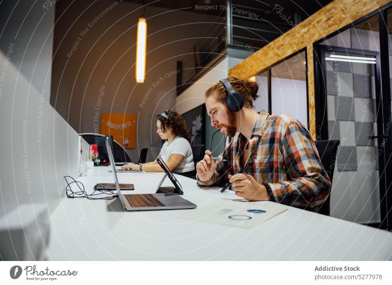 Konzentrierter Mann und Frau arbeiten im Büro mit Geräten Kopfhörer Tippen benutzend Tablette Laptop Arbeit Job Fokus Kollege Mitarbeiter Inbetriebnahme