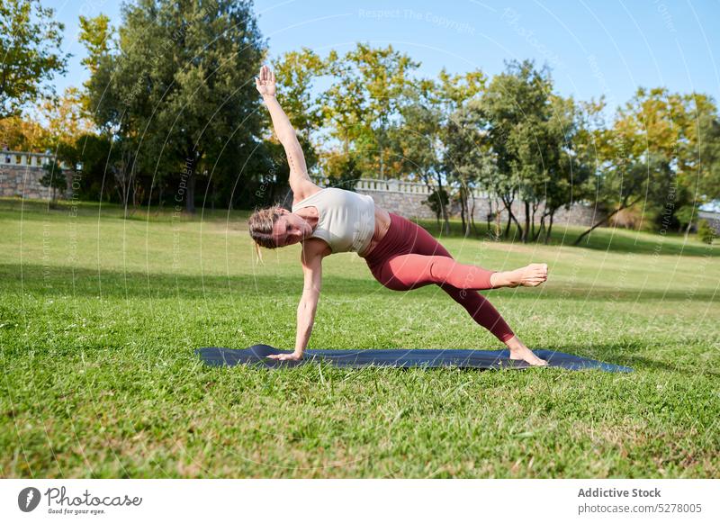 Schlanke Frau übt Yoga mit seitlichem Plankenkick Asana Seitwärtssalto üben Training Unterlage beweglich Motivation Park Übung schlank Gesundheit Wellness