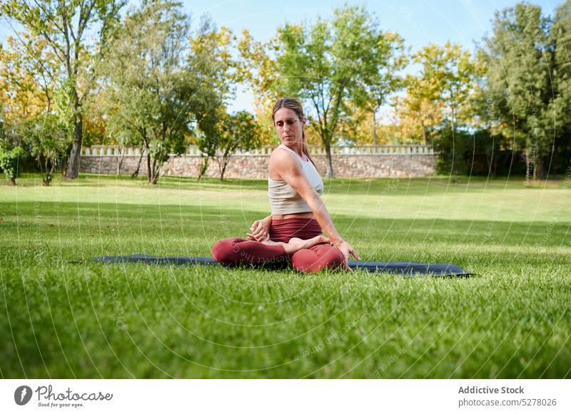 Konzentrierte Frau beim Yoga in sitzender Twist-Pose Asana sitzende Drehung Beine gekreuzt Parivritta Sukhasana meditieren Sprit Stressabbau Gesunder Lebensstil