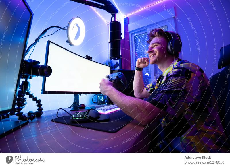 Fröhlicher Mann spielt Computerspiel Spieler positiv Luftschlange e Sportarten Lächeln spielen Videospiel Joystick online neonfarbig unterhalten Gamepad