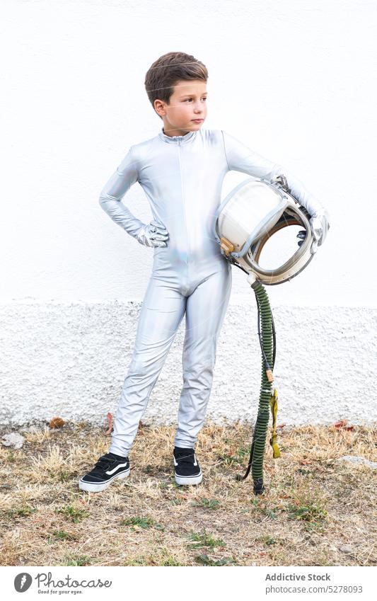 Kind im Raumanzug hält Helm in der Landschaft Junge Kosmonaut Astronaut Raumfahrer Entdecker Schutzhelm futuristisch träumen Tracht Zukunft stehen altmodisch