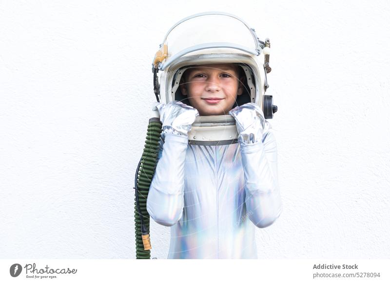 Junge im Raumanzug schaut in die Kamera Kind Kosmonaut Astronaut Lächeln Raumfahrer Glück Entdecker futuristisch nachdenklich Atelier stehen Schutzhelm