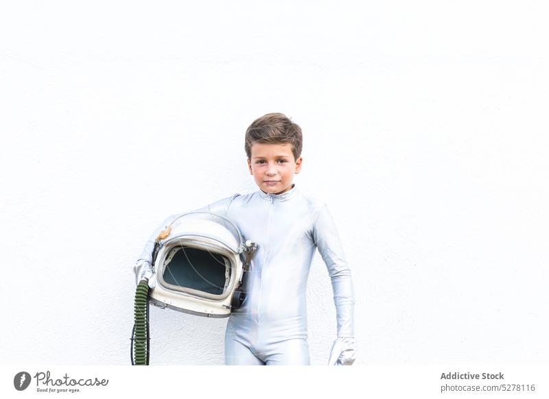 Kind im Raumanzug steht auf grasbewachsenem Boden Junge Kosmonaut Astronaut Raumfahrer Entdecker Schutzhelm verdorren futuristisch Tracht Zukunft stehen