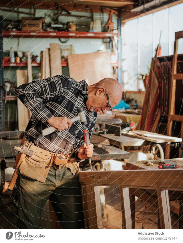 Senior Schreiner mit Meißel und Hammer in der Werkstatt Mann Beitel Tischlerin geschnitten Kunsthandwerker Schiffsplanken Holz Fähigkeit Kunstgewerbler