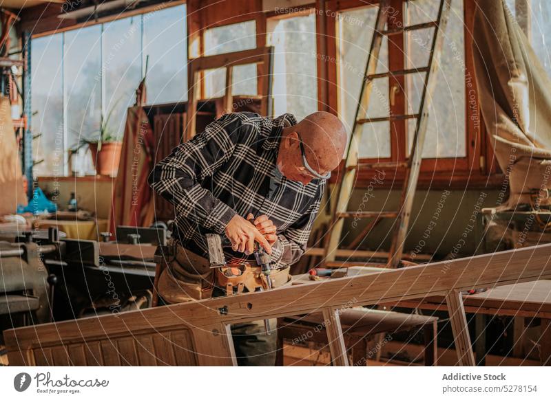 Holzarbeiter beim Bohren eines Holzbretts in einer Tischlerei Mann bohren Zimmerer Tischlerin Schiffsplanken Werkstatt Tischlerarbeit professionell Schreinerei