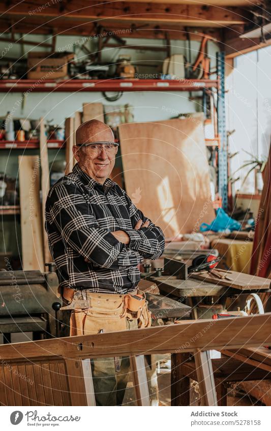 Älterer Handwerker schaut in der Werkstatt auf die Kamera Mann Zimmerer Lächeln Glück Tischlerarbeit professionell Arbeit heiter Job Kunstgewerbler männlich