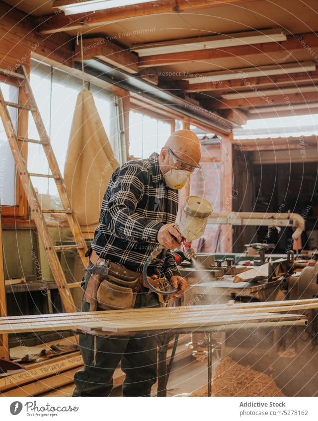 Schreiner bei der Arbeit mit einem Farbspritzgerät in der Werkstatt Mann Firnis Zimmerer Holzplatte Tischlerin Farbe Mundschutz Tischlerarbeit polnisch
