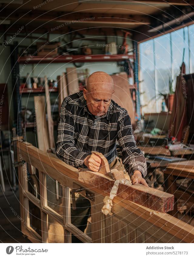 Älterer Tischler bei der Arbeit mit der Tischlerbank in der Werkstatt Mann Zimmerer Abrichthobelmaschine Tischlerin geschnitten Holz Holzarbeiten Hobelbank