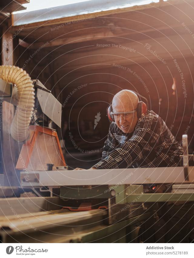 Tischler schneidet Holz auf Tischkreissäge Mann Säge Zimmerer Holzarbeiten Tischlerarbeit Schiffsplanken geschnitten Tischlerin kreisrund Kopfhörer Werkstatt