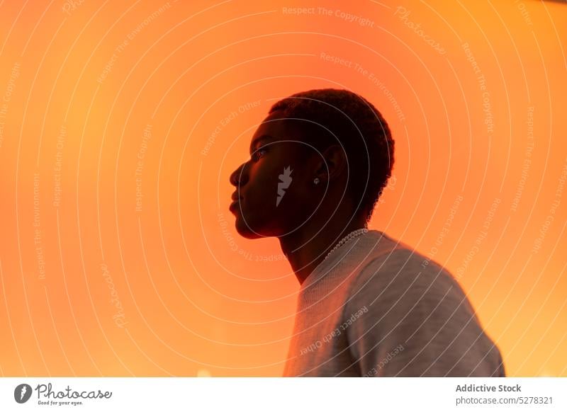 Nachdenklicher schwarzer Mann im Studio besinnlich nachdenklich Windstille ernst neonfarbig Licht Persönlichkeit selbstbewusst leuchten männlich lässig