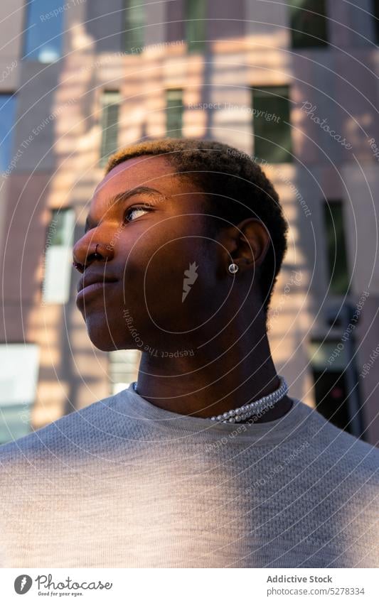 Ernster schwarzer Mann auf der Straße Vorschein Großstadt Stil selbstbewusst maskulin Outfit Gebäude Ohrringe trendy männlich ernst afroamerikanischer Mann