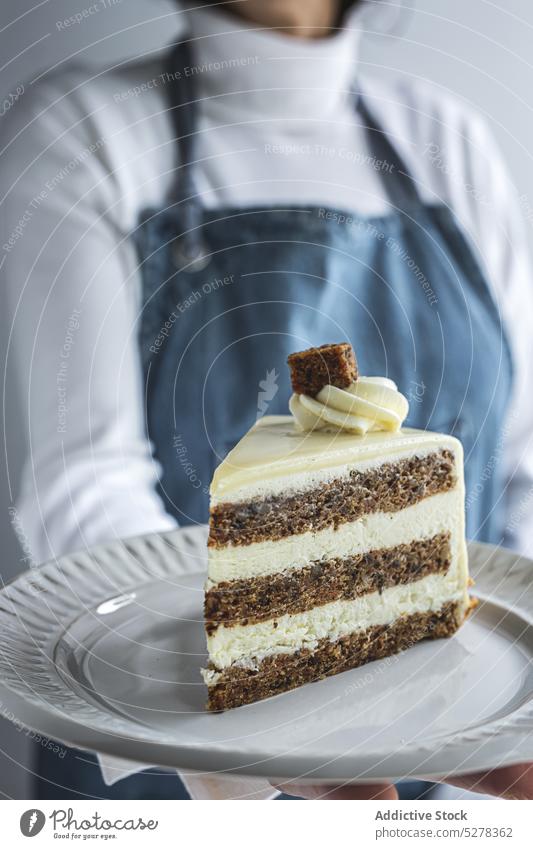 Anonymer Zuckerbäcker serviert Dessert auf einem Teller Frau Konditor Kuchen Portion dienen Sahne süß Glasur Gebäck Spielfigur lecker weiß gepeitscht Konditorei