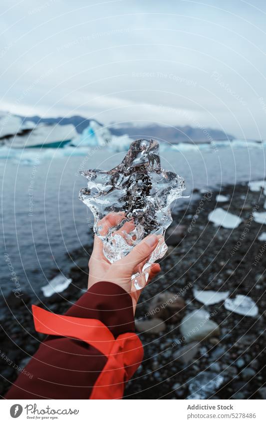Crop-Frau mit transparentem Eis Reisender zeigen Ufer MEER durchsichtig kalt Winter Oberbekleidung Island Spielfigur Wetter gefroren Küste Wasser manifestieren