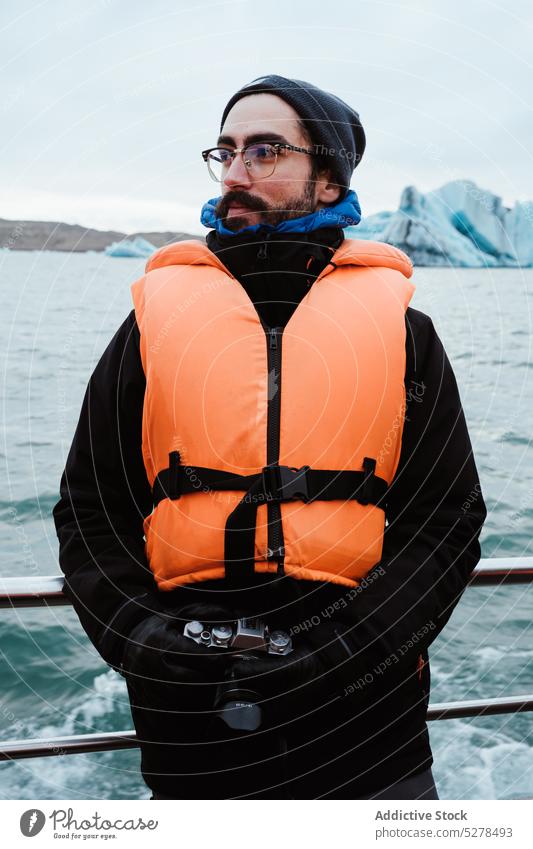 Männlicher Fotograf auf einem Schiff im Meer Mann MEER Winter Fotoapparat Ausflug wolkig kalt reisen Island Ufer Oberbekleidung Gefäße Schwimmweste Himmel