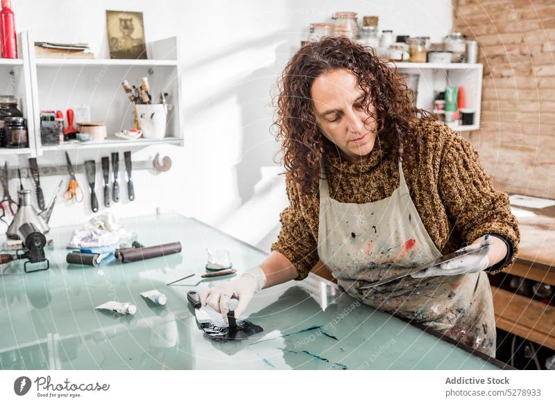 Weiblicher Handwerker bei der Prüfung einer Metallplatte Handwerkerin untersuchen Teller Fotogravur Atelier Schwamm Tusche vorbereiten kreativ Industrie Frau