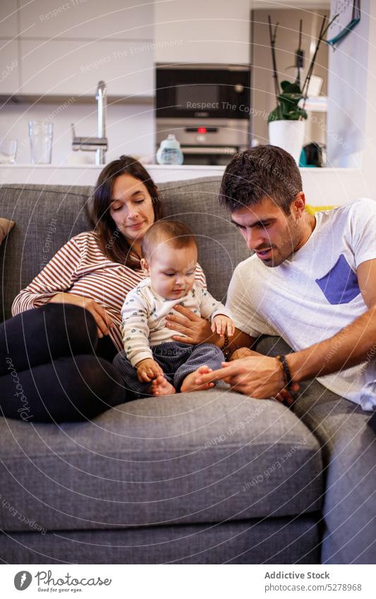 Glückliche Eltern mit Baby auf dem Sofa Familie spielen positiv Zusammensein Partnerschaft heimwärts Zeit verbringen Liebe Kind Mutter Wohnzimmer Kindheit Vater