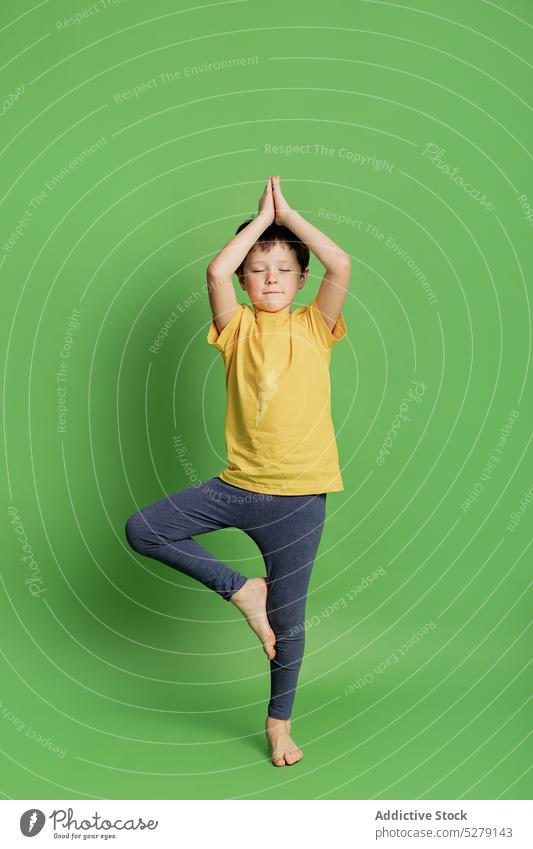 Ruhiger Junge übt Baumpose Kind Windstille Yoga Baumhaltung Asana üben Sportbekleidung Gleichgewicht Wellness Pose Barfuß Atelier Gesundheit Kindheit