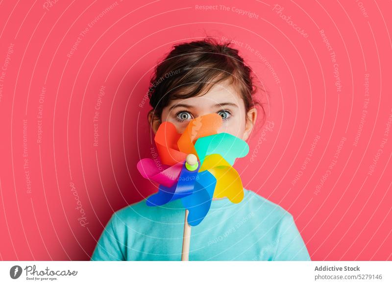 Lustiges Mädchen mit Regenbogen-Pinnrad Kind Windrad sorgenfrei Kindheit lustig spielerisch Spielzeug Deckblatt erstaunt Persönlichkeit expressiv farbenfroh