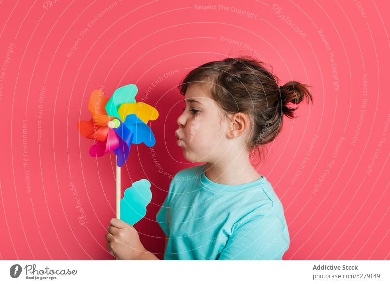 Lustiges Kind, das auf ein Windrad bläst Mädchen Schlag Regenbogen spielen Freizeit unterhalten Interesse Spiel lustig spielerisch heiter Spielzeug