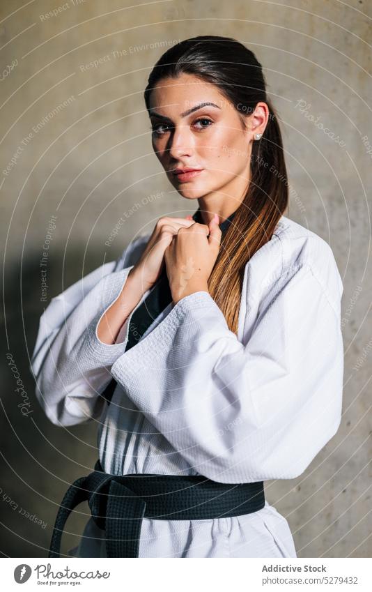 Selbstbewusste Frau im Taekwondo-Mantel Uniform selbstbewusst ernst tausendjährig Gurt Beton Meister Beruf jung Arbeit professionell stehen Konzentration