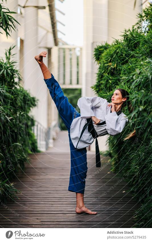 Ernste Frau übt Taekwondo auf der Straße Kick selbstbewusst professionell Training Fähigkeit üben Sport Karate Gurt Athlet Uniform Kämpfer Aktivität stark