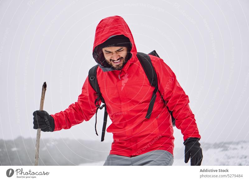 Mann in Oberbekleidung geht mit Stock auf verschneitem Terrain Wanderer Wanderung Spaziergang Reisender Fernweh Schnee Wetter kalt Tourismus männlich Tourist