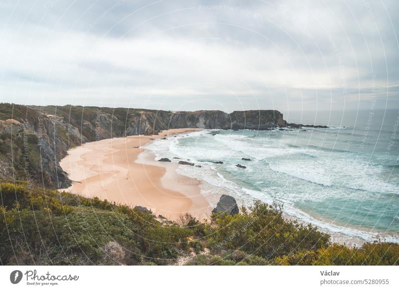 Berühmter Strand Praia dos Machados in Odemira, Westportugal. Die Felsen, die den mondförmigen Sandstrand umgeben, werden von den hohen Wellen des Atlantischen Ozeans umspült. Fischerpfad