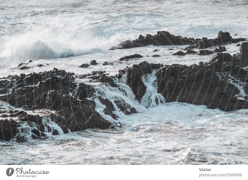 Das stürmische Meer beweist seine Stärke. Während des Sonnenuntergangs in der Region Odemira im Westen Portugals schlagen die Wellen gegen einen Felsen. Wanderung auf dem Fischerpfad, Rota Vicentina